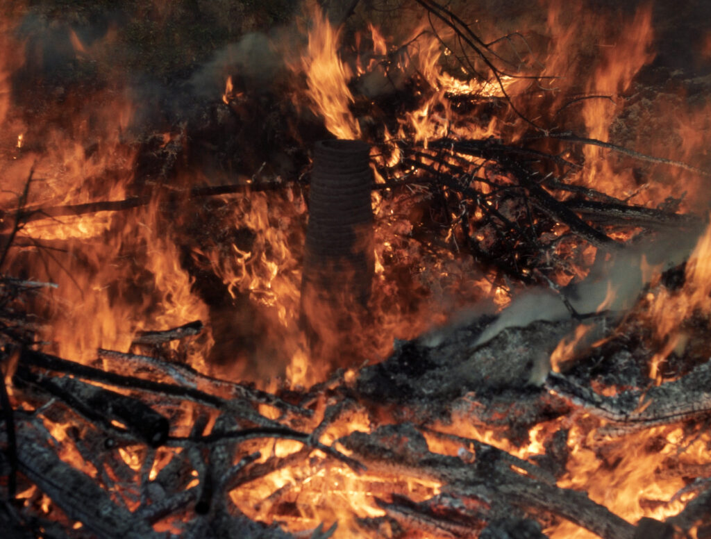 La peça enmig del foc, envoltada de branques cremant